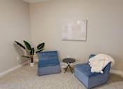 Thumbnail 15 of 15 - A living room with a blue chair and a small table.