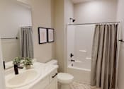 Thumbnail 14 of 15 - A bathroom with a white sink, toilet, and shower curtain.
