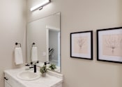 Thumbnail 13 of 15 - A bathroom with a white sink and a mirror above it.