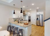 Thumbnail 3 of 15 - A kitchen with a white counter top and stools.