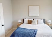 Thumbnail 9 of 15 - A bedroom with a bed, two nightstands, and a picture on the wall.