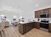 Thumbnail 11 of 17 - A modern kitchen with wooden floors and stainless steel appliances.