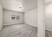 Thumbnail 15 of 28 - A sparsely furnished room with a window and carpeted floor.