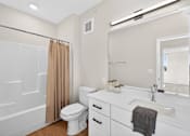 Thumbnail 11 of 19 - A white bathroom with a toilet, sink, and shower.