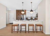 Thumbnail 19 of 19 - A kitchen with a white counter and brown stools.