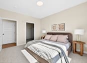 Thumbnail 9 of 19 - A bedroom with a bed, nightstand, and two doors.