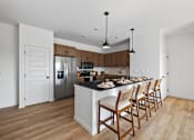 Thumbnail 23 of 25 - A kitchen with wooden chairs and a black countertop.