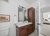 Thumbnail 19 of 25 - A bathroom with a white sink and brown cabinet.