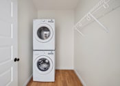 Thumbnail 18 of 25 - A white dryer and washer are stacked on top of each other in a small room.