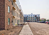 Thumbnail 24 of 25 - A construction site with a row of unfinished buildings on the left and a row of finished buildings on the right.