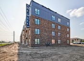 Thumbnail 9 of 25 - A large building with a blue sign on top of it.