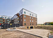 Thumbnail 11 of 25 - A large building under construction with a red truck parked in front.