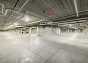 Thumbnail 60 of 61 - A large, empty parking garage with a concrete floor and white walls.
