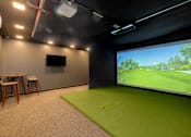 Thumbnail 7 of 61 - A room with a green carpet and a large screen on the wall.