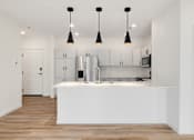 Thumbnail 49 of 61 - A kitchen with a white island and pendant lights.