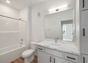 Thumbnail 54 of 61 - A white bathroom with a marble countertop and a large mirror.