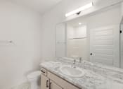 Thumbnail 56 of 61 - A white bathroom with a toilet, sink, and mirror.