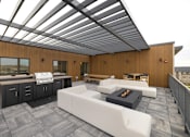 Thumbnail 8 of 61 - A modern outdoor living space with a white couch and a fireplace.