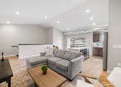 Thumbnail 9 of 76 - A modern living room with a grey sofa and a wooden coffee table.