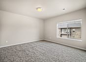 Thumbnail 31 of 39 - A room with a carpeted floor and a window showing a view of a building.