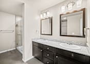 Thumbnail 32 of 39 - A bathroom with two sinks and a large mirror.