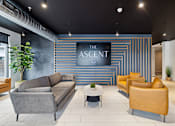 Thumbnail 2 of 88 - A modern waiting room with a grey sofa and leather armchair.