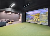 Thumbnail 4 of 88 - A golf simulator room with a large screen on the wall and a couch.