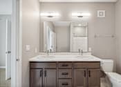 Thumbnail 66 of 88 - A bathroom with double vanity with wood-toned cabinets.