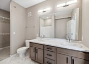 Thumbnail 65 of 88 - A bathroom with double vanity with wood-toned cabinets.