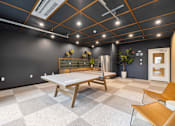 Thumbnail 46 of 88 - A room with a ping pong table, chairs and a fridge.