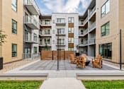 Thumbnail 80 of 88 - A modern apartment complex with a central courtyard and seating area.
