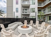 Thumbnail 76 of 88 - A modern patio with a fire pit and chairs.