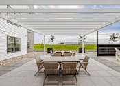 Thumbnail 86 of 88 - A patio with a table and chairs is covered by a white roof.