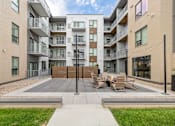 Thumbnail 81 of 88 - A modern apartment complex with a courtyard and seating area.