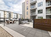 Thumbnail 73 of 88 - A modern apartment complex with a patio area in the foreground.