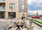 Thumbnail 79 of 88 - A patio with chairs and a fire pit in front of a modern building.