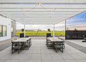 Thumbnail 77 of 88 - A patio with two tables and chairs under a white roof.
