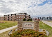 Thumbnail 2 of 37 - The Cedars apartment complex is surrounded by a well-maintained lawn and a clear sky.