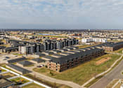 Thumbnail 37 of 37 - A large apartment complex is surrounded by smaller buildings and a road.