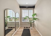 Thumbnail 18 of 61 - A room with a mirror, a yoga mat, and a plant.