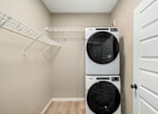 Thumbnail 29 of 61 - A white dryer and washer are stacked on top of each other in a laundry room.