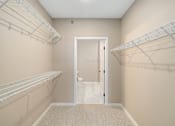 Thumbnail 22 of 61 - A walk-in closet with white shelving and a carpeted floor.