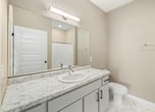 Thumbnail 23 of 61 - A bathroom with a marble countertop and a white toilet.