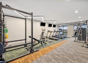 Thumbnail 23 of 88 - a gym with a row of weights machines and a wall of windows