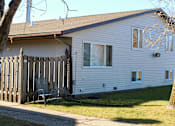 Thumbnail 2 of 18 - A white house with a brown roof and a grey chair in front of it.