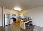 Thumbnail 1 of 36 - A kitchen with a refrigerator, microwave, oven, and bar stools.