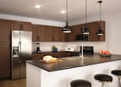 Thumbnail 2 of 3 - A modern kitchen with a refrigerator, sink, and bar stools.