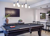 Thumbnail 41 of 58 - A pool table in a room with a TV on the wall.