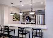 Thumbnail 40 of 58 - A kitchen with a white counter and black chairs.