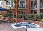 Thumbnail 26 of 58 - A small hot tub sits in the middle of a brick patio.